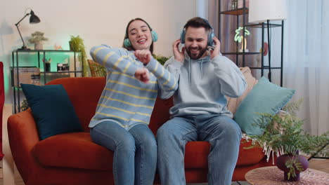 Family-man-woman-in-wireless-headphones-dancing-listening-favorite-rock-n-roll-music-on-home-couch