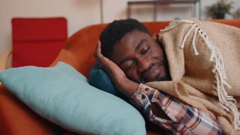 African-american-young-man-sleeping-quietly-in-bedroom-at-home,-smiling,-lying-on-comfortable-bed