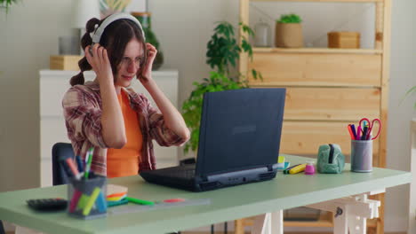 A-Young-Girl-Works-on-a-Laptop-and-Puts-on-Headphones