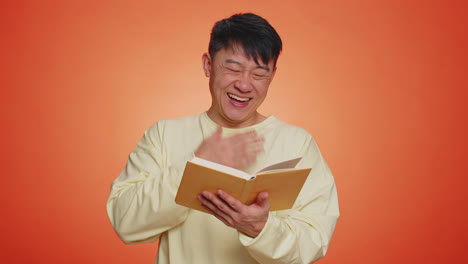 Happy-chinese-man-reading-funny-interesting-fairytale-story-book,-leisure-hobby,-education,-learning