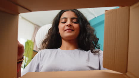 Happy-Indian-woman-shopper-unpacking-cardboard-box-delivery-parcel-online-shopping-purchase-at-home