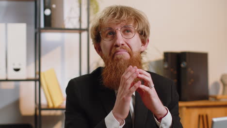 Confident-happy-redhead-businessman-in-glasses-looking-at-camera-with-smile-at-home-office-workplace