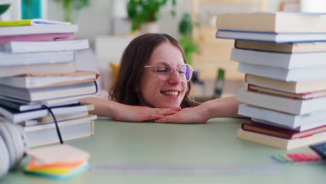 Portrait-of-a-Smiling-Young-Student-Looking-at-Piles-of-Books-to-Read