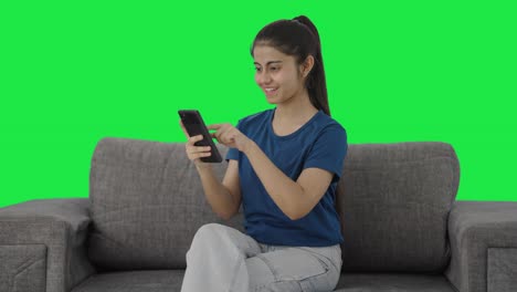 Happy-Indian-teenage-girl-scrolling-phone-Green-screen