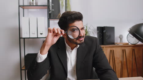 Business-man-holding-magnifying-glass-near-face,-looking-with-big-zoomed-eye,-searching,-analysing