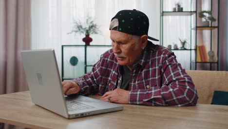 Stressed-upset-senior-grandfather-man-working-on-laptop-computer,-received-bad,-loss-news-at-home