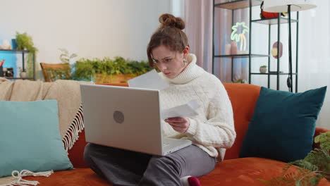 Stressed-young-woman-looking-at-unpaid-bank-debt-loan,-doing-paperwork,-planning-budget-throws-bills