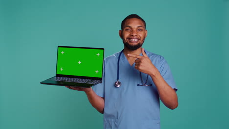 Portrait-of-male-nurse-showing-medical-instructions-video-on-green-screen-tablet