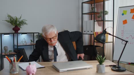 Smiling-mature-business-man-sits-at-workplace-office-desk,-opening-laptop-computer,-start-working