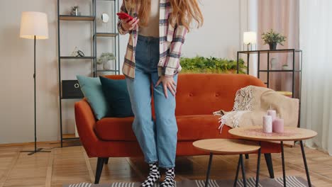 Cheerful-young-woman-sitting-on-sofa,-using-mobile-phone-share-messages-on-social-media-application