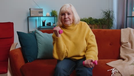 Abuela-Mayor-Haciendo-Ejercicios-De-Fitness-Con-Pesas-Y-Pesas,-Entrenando-Fuerza-En-Casa