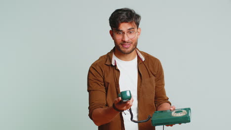 Indian-man-talking-on-wired-landline-vintage-telephone,-advertising-proposition-of-conversation