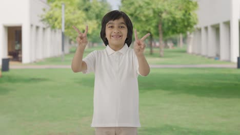 Happy-Indian-boy-showing-victory-sign-in-park