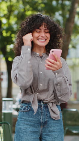 Caucasian-woman-use-mobile-smartphone-celebrating-win-good-message-news-outdoors-on-city-street