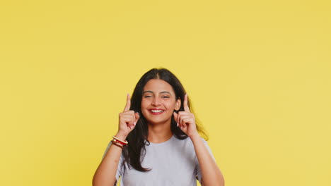 Young-woman-showing-thumbs-up-and-pointing-overhead-on-blank-space-place-for-your-advertisement-logo