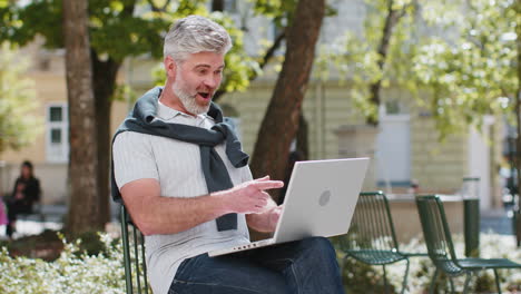 Mature-man-using-laptop-computer-celebrating-win-good-message-news-lottery-jackpot-casino-victory