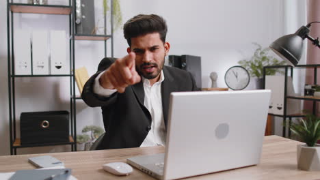 Hombre-De-Negocios-Trabajando-En-Una-Computadora-Portátil-De-Oficina-Apuntando-A-La-Cámara-Mirando-Con-Expresión-Feliz-Haciendo-Elecciones