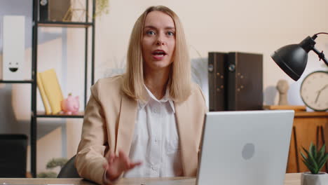 Business-woman-works-on-office-laptop-pointing-to-camera-looking-with-happy-expression-making-choice