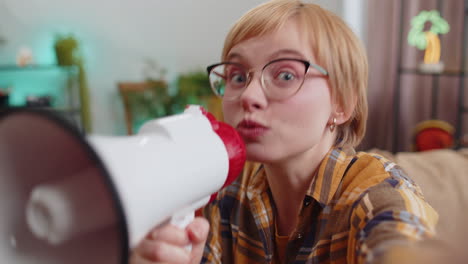 Young-woman-talking-with-megaphone,-proclaiming-news,-loudly-announcing-advertisement-at-home-room