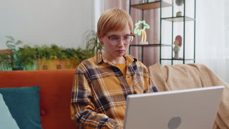 Young-woman-freelancer-sitting-on-couch-closing-laptop-pc-after-finishing-work-in-room-at-home