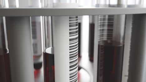 Blood-samples-in-a-test-tube-centrifuge.-Bunch-of-tubes-with-red-liquid-inside-in-a-laboratory-interior-blurred-by-camera-depth-of-field.-Efficient-sample-analysis.--A-slow-elevation-camera-movement.