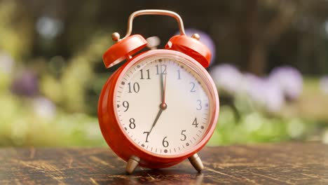 Old-vintage-red-alarm-clock-standing-on-a-wooden-office-desk.-Bells-ring-and-clock-shakes-on-time.-Office-workstation-in-a-background.-Symbol-of-morning,-countdown,-deadline.--Classic-ageless-design.