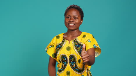 Cheerful-positive-woman-showing-thumbs-up-gesture-in-studio