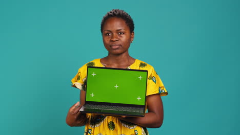 Confident-smiling-woman-presenting-a-chroma-key-display-on-laptop