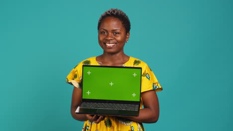 Optimistic-gorgeous-girl-holding-a-pc-with-isolated-green-screen