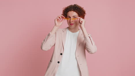 Stylish-smiling-Caucasian-young-man-with-curly-hair-wearing-orange-sunglasses-glad-expression