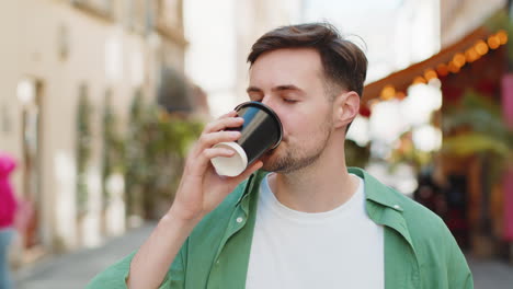 Hombre-Feliz-Disfrutando-De-Una-Bebida-Caliente-De-Café-Por-La-Mañana-Y-Sonriendo-Relajándose,-Tomando-Un-Descanso-En-Las-Calles-De-La-Ciudad