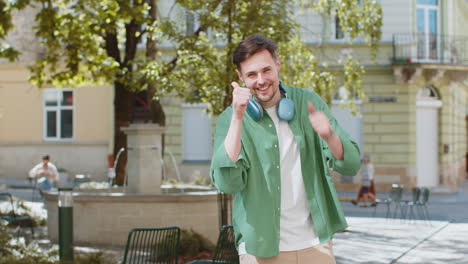 Hombre-Feliz-Turista-Mostrando-Los-Pulgares-Hacia-Arriba-Como-Algo-Positivo-Buena-Retroalimentación-Positiva-En-Las-Calles-De-La-Ciudad