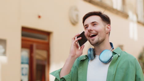 Man-tourist-having-remote-conversation-communicate-speaking-by-smartphone-with-friend-good-news