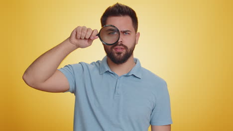 Investigator-researcher-man-with-magnifying-glass-near-face,-looking-into-camera-with-big-zoom-eye