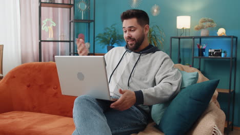 Man-sitting-on-home-couch,-looking-at-camera,-making-video-conference-call-with-friends-or-family