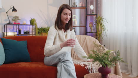 Thirsty-young-woman-sitting-at-home-holding-glass-of-natural-aqua-make-sips-drinking-still-water