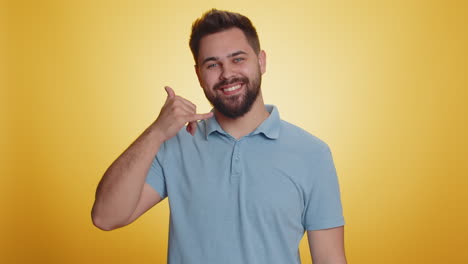 Bearded-young-man-looking-at-camera-doing-phone-gesture-like-says-hey-you-call-me-back-conversation