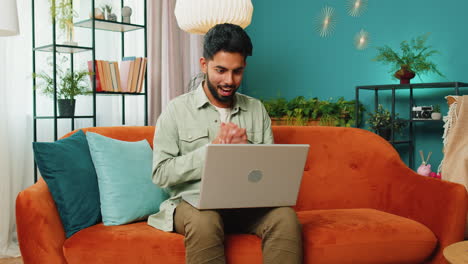 Amazed-Indian-man-use-laptop-computer,-receive-good-news-message,-shocked-by-victory,-celebrate-win