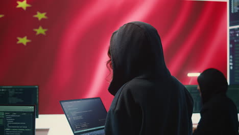 Chinese-hacker-working-in-governmental-hacking-room-with-Chinese-flag