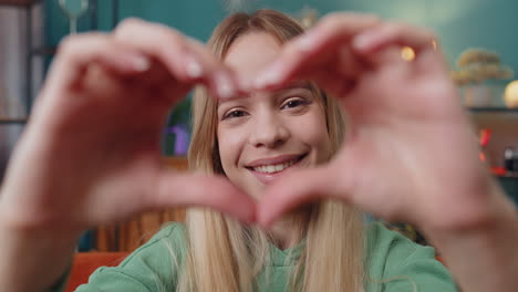 Happy-young-woman-girl-makes-symbol-of-love-showing-heart-sign-to-camera-express-romantic-feelings