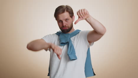 Upset-handsome-man-guy-in-t-shirt-showing-thumbs-down-sign-gesture,-disapproval-dissatisfied-dislike