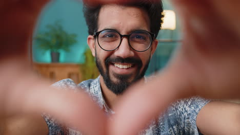 Happy-indian-man-guy-makes-symbol-of-love-showing-heart-sign-to-camera-express-romantic-feelings