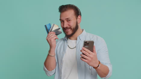 Lebanese-man-using-credit-bank-cards,-smartphone-while-transferring-money-purchases-online-shopping