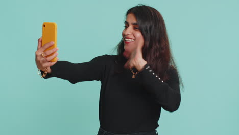 Indian-woman-traveler-blogger-taking-selfie-on-smartphone-communicating-video-call-online-stream