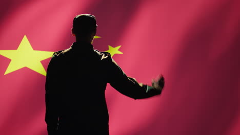 Soldier-doing-salute-hand-gesture-towards-Chinese-flag