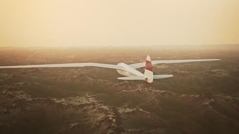 Una-Vista-Aérea-Del-Planeador-Blanco-Sin-Hélice-Deslizándose-Tranquilamente-En-El-Cielo,-Sobre-Montañas-Cubiertas-De-Nieve.-Volar-Aviones-Aerodinámicos-Es-Una-Excelente-Manera-De-Pasar-El-Tiempo-Libre.