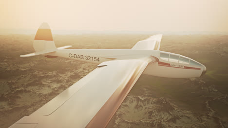 Una-Vista-Aérea-Del-Planeador-Blanco-Sin-Hélice-Deslizándose-Tranquilamente-En-El-Cielo,-Sobre-Montañas-Cubiertas-De-Nieve.-Volar-Aviones-Aerodinámicos-Es-Una-Excelente-Manera-De-Pasar-El-Tiempo-Libre.