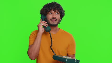 Crazy-funny-indian-man-talking-on-wired-vintage-telephone-of-80s,-fooling,-making-silly-faces