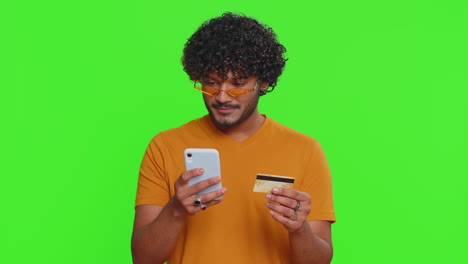 Indian-man-using-credit-bank-card-and-smartphone-while-transferring-money-purchases-online-shopping