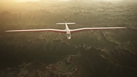 Una-Vista-Aérea-Del-Planeador-Blanco-Sin-Hélice-Deslizándose-Tranquilamente-En-El-Cielo,-Sobre-Montañas-Cubiertas-De-Nieve.-Volar-Aviones-Aerodinámicos-Es-Una-Excelente-Manera-De-Pasar-El-Tiempo-Libre.